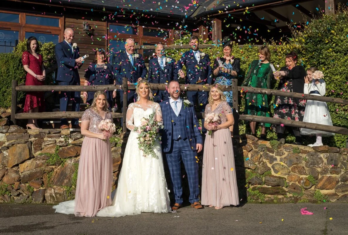 A group of wedding party with confetti thrown at them.