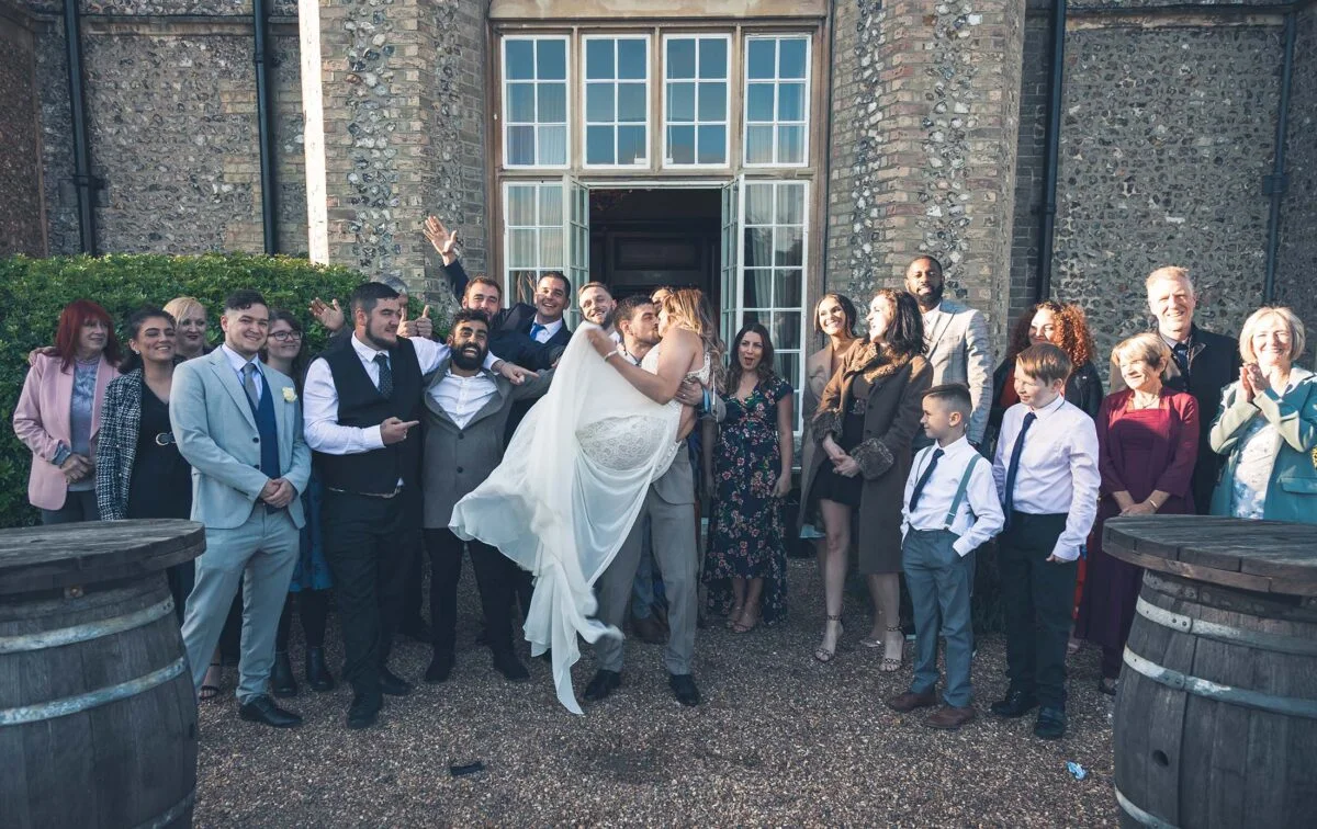 A bride and groom with their wedding party in front of barrels.
