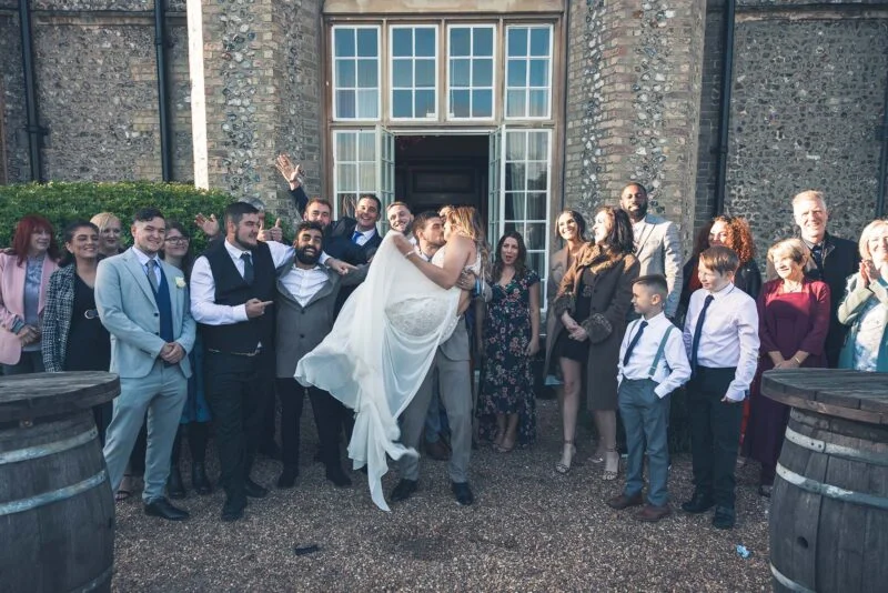 A bride and groom with their wedding party in front of barrels.
