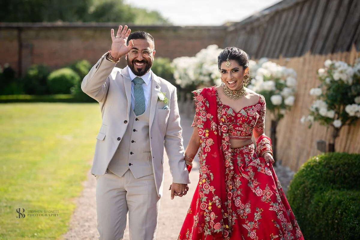 A bride and groom walking through a garden.