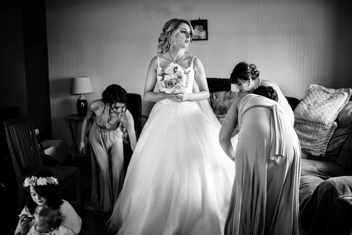 A bride getting ready in a room with her bridesmaids.