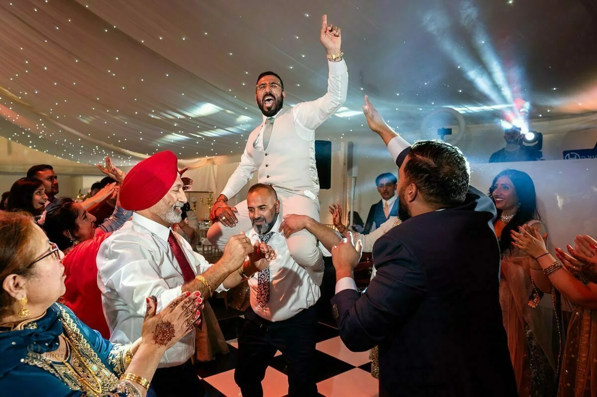 A man in a turban is being thrown into the air at a wedding reception.