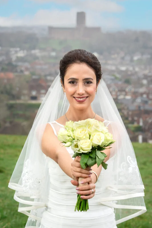 A bride holding a bouquet in front of a castle.