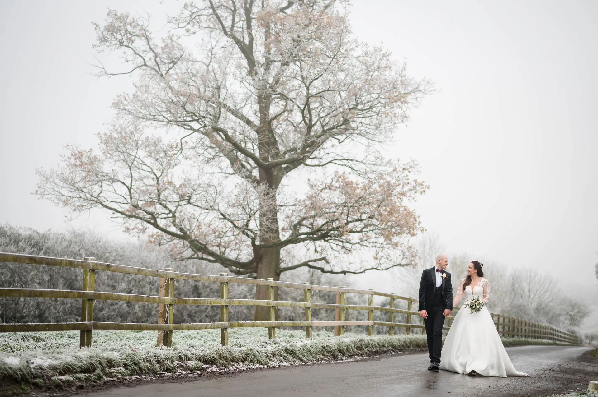 Cheap wedding photographer London captures a bride and groom walking down the road in the snow. (listing)