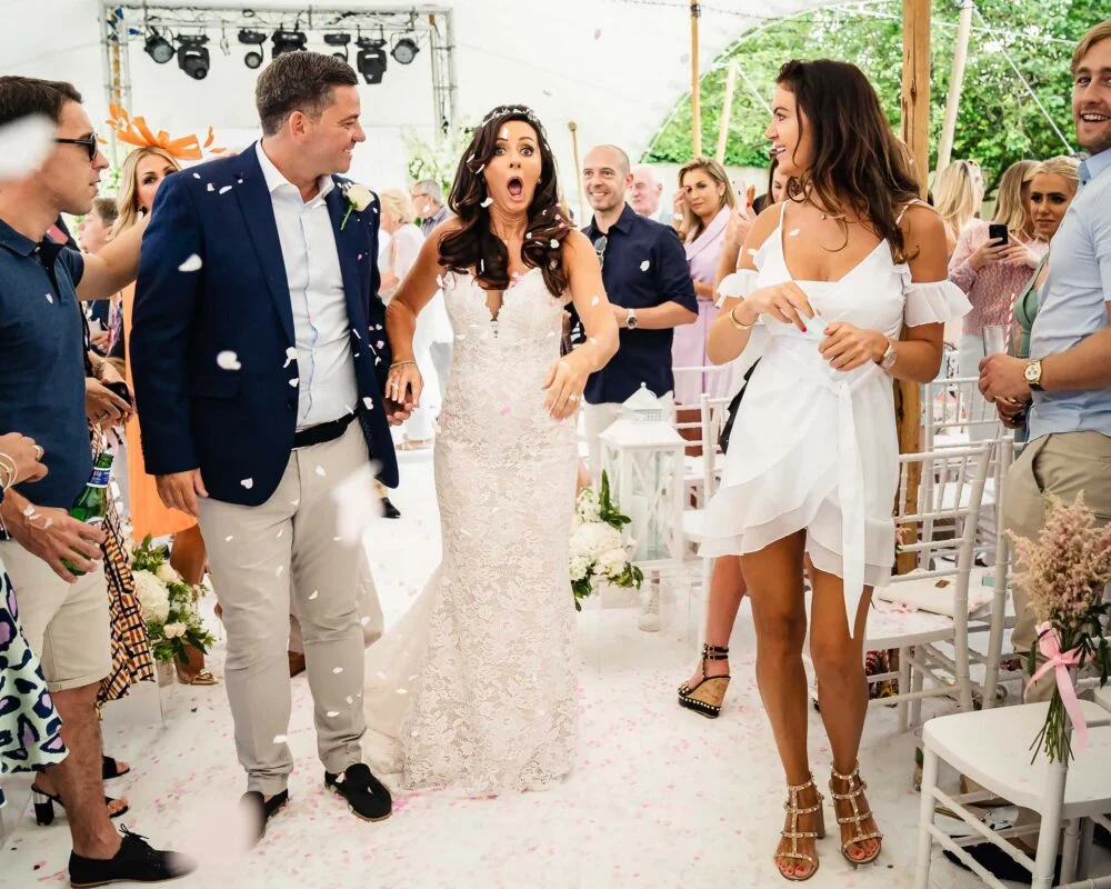 A bride and groom walk down the aisle with confetti thrown at them.