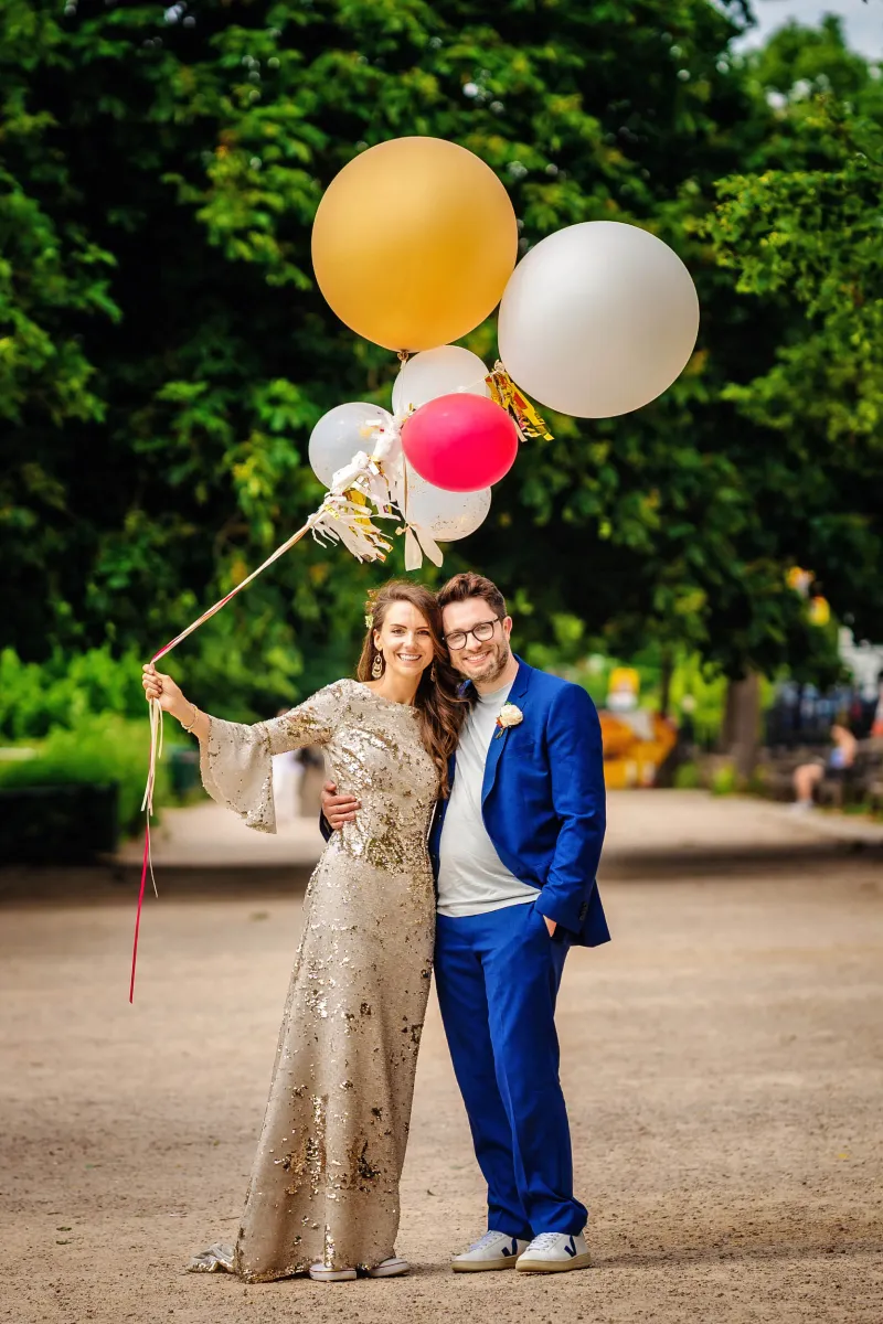 Cheap wedding photographer in London capturing a bride and groom holding balloons in a park. (listing)