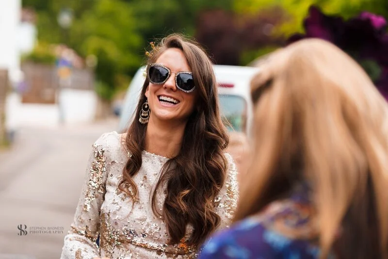 A woman in a sequined dress is laughing with another woman.