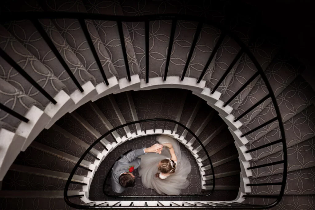 A bride and groom on a spiral staircase.