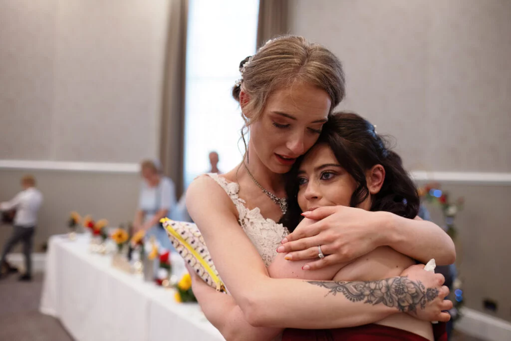 Two women hugging each other at a wedding reception.