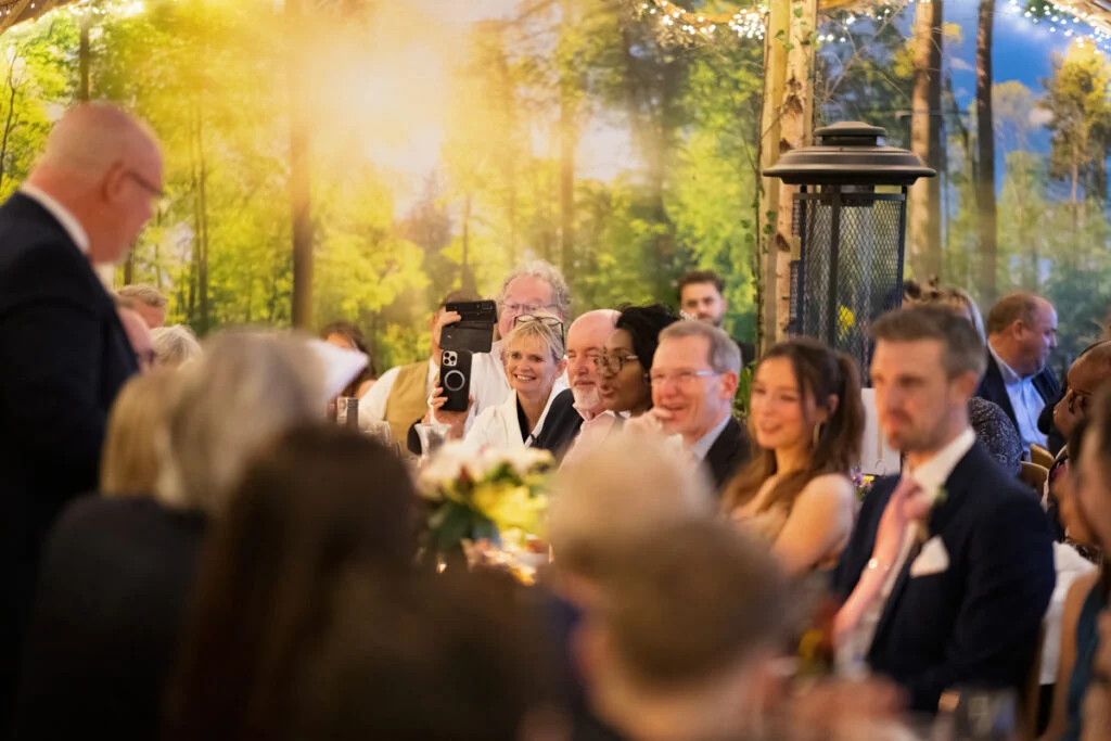 A group of people sitting at a table in a wooded area.