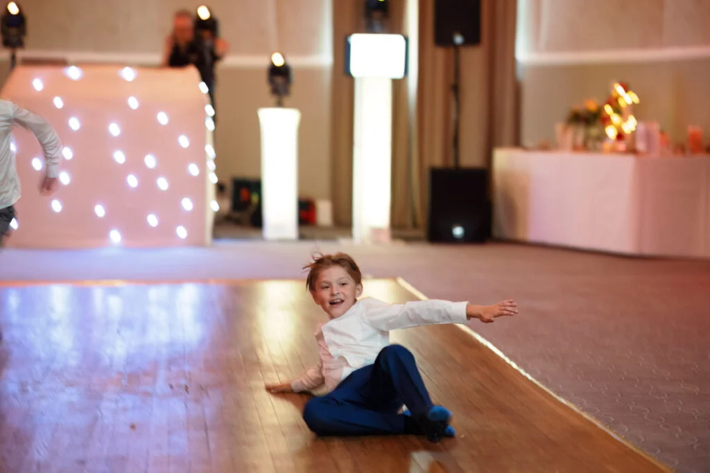 Two children playing on the floor at a wedding reception.