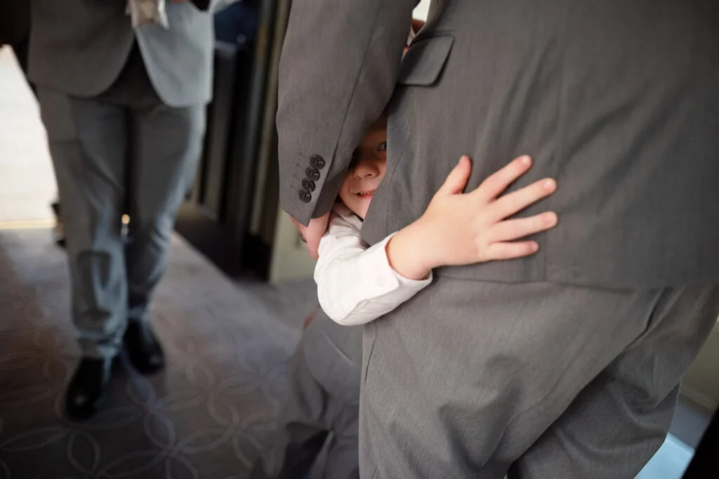 A little boy is hugging a man in a suit.