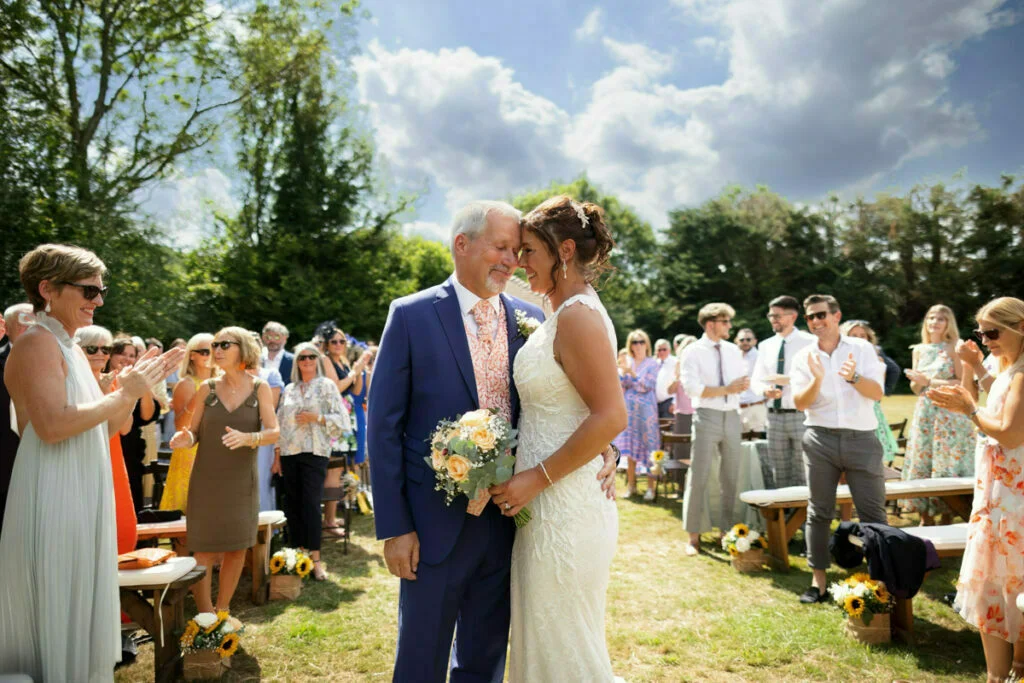 A bride and groom kiss in front of a crowd of people.