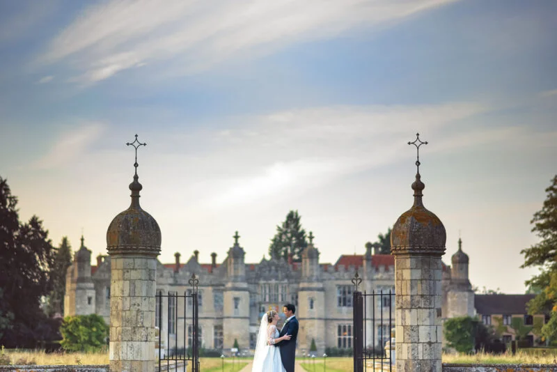 A bride and groom standing in front of a castle.