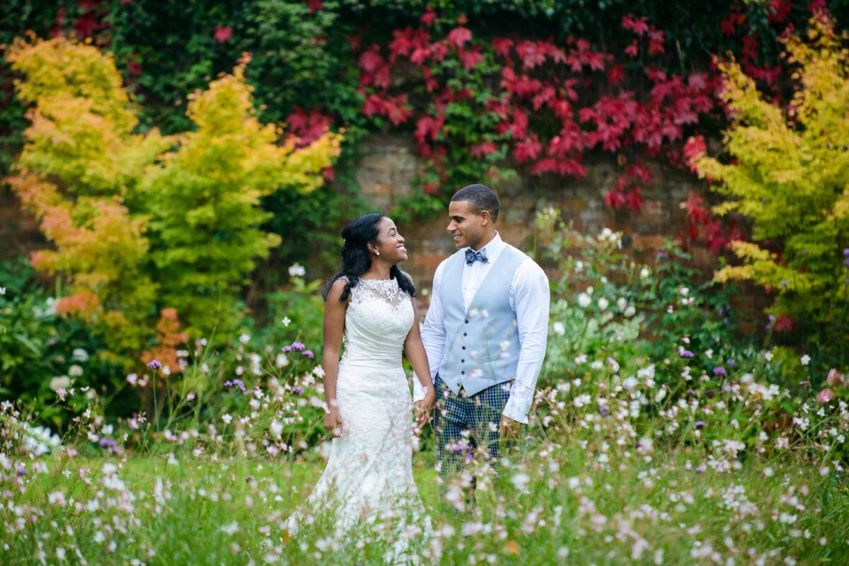 A bride and groom standing in a field of flowers.