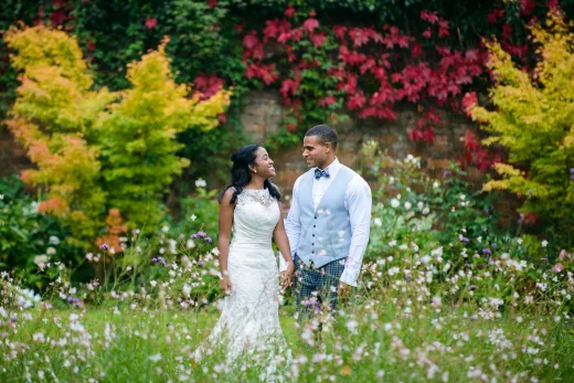 A bride and groom standing in a field of flowers.
