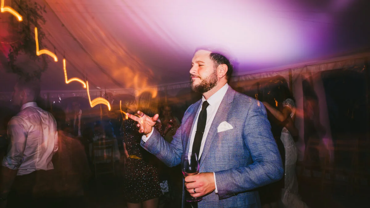 A man in a suit dancing at a wedding.
