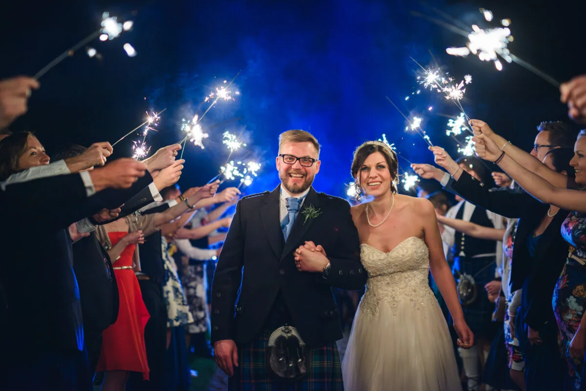 A bride and groom with sparklers in their hands.