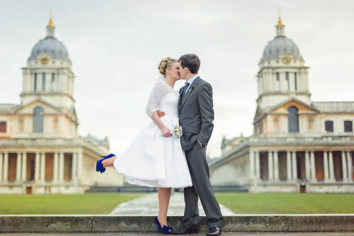 A bride and groom kissing in front of an old building.