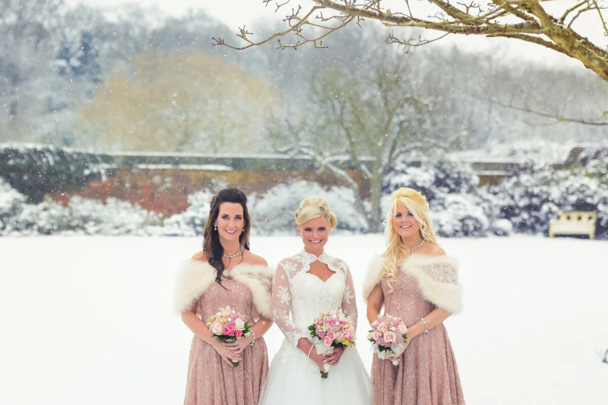 Three bridesmaids standing in the snow.