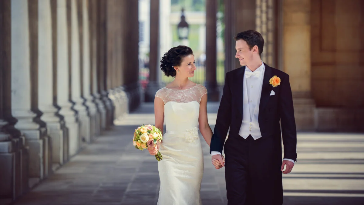 A bride and groom walking through an archway.