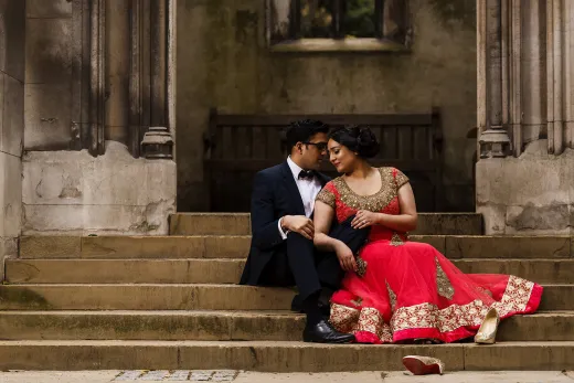 A bride and groom sitting on the steps of an old building.