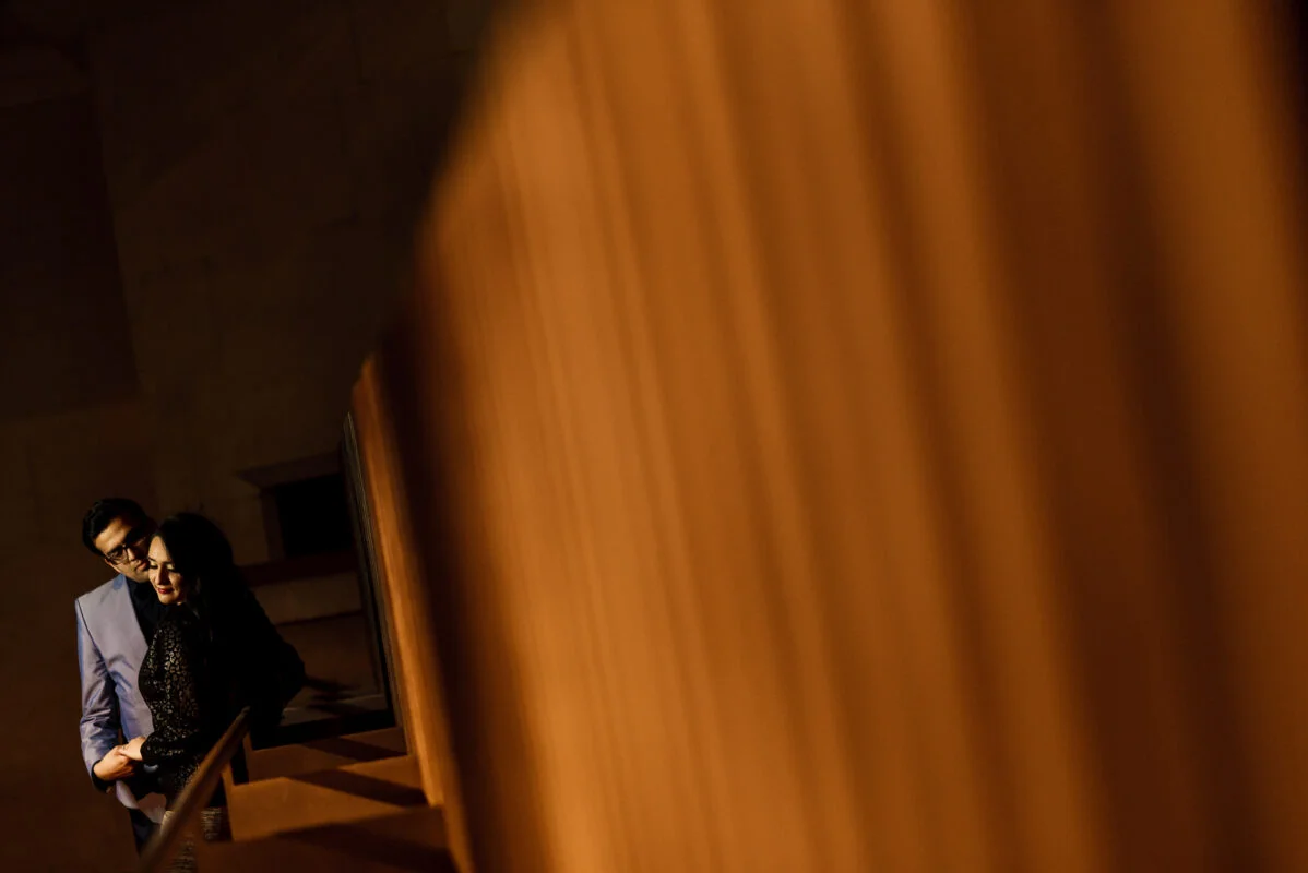 A man and woman standing on a staircase in a dark room.
