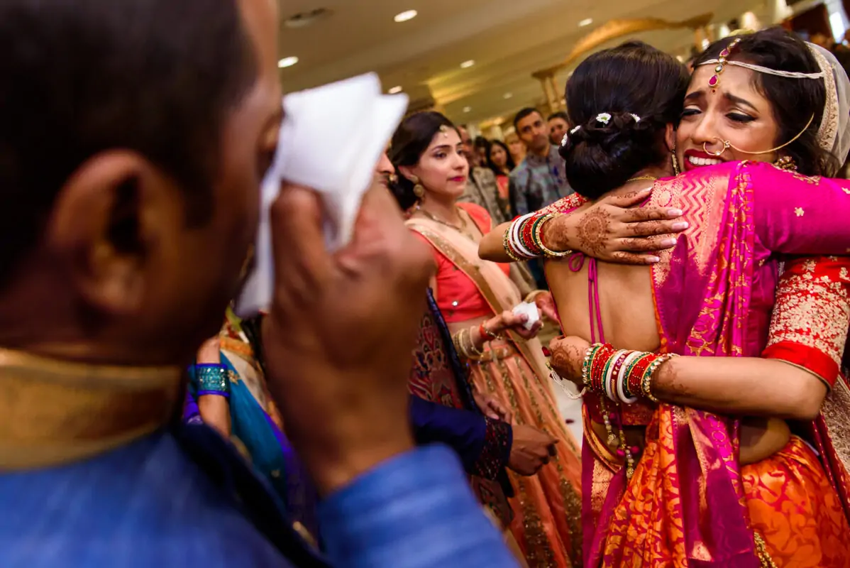 An indian bride hugging her bridesmaids.