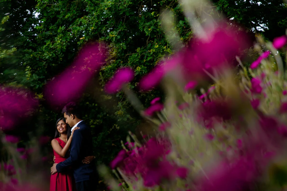 A couple embracing in a field of pink flowers.