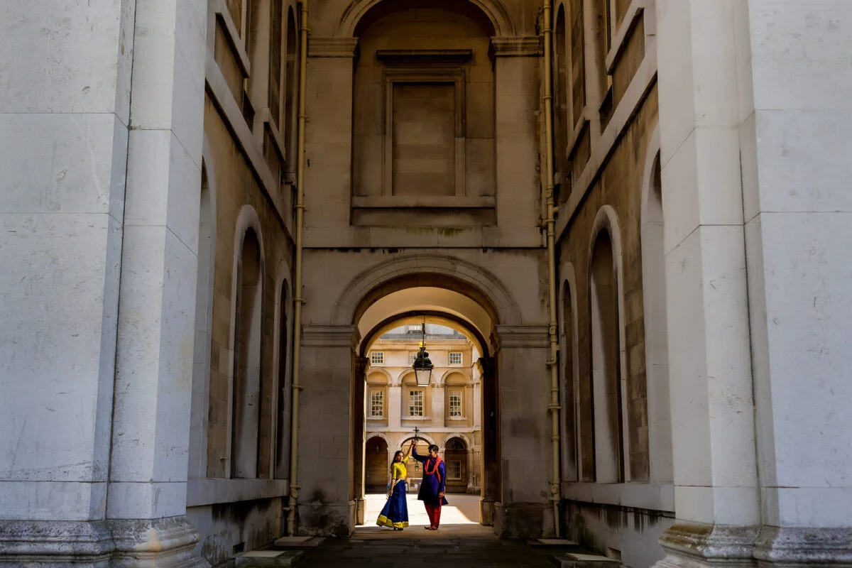 A couple walking through an archway in a building.