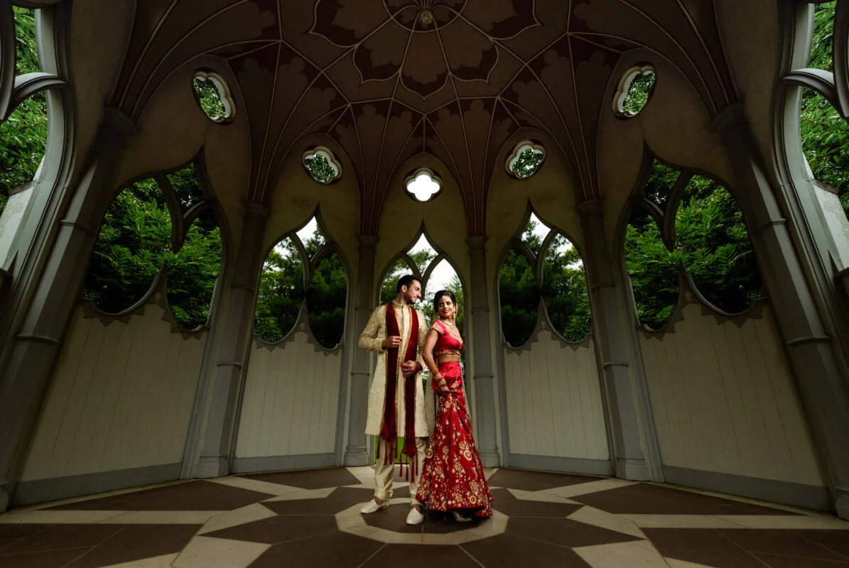 An indian bride and groom standing in an ornate room.