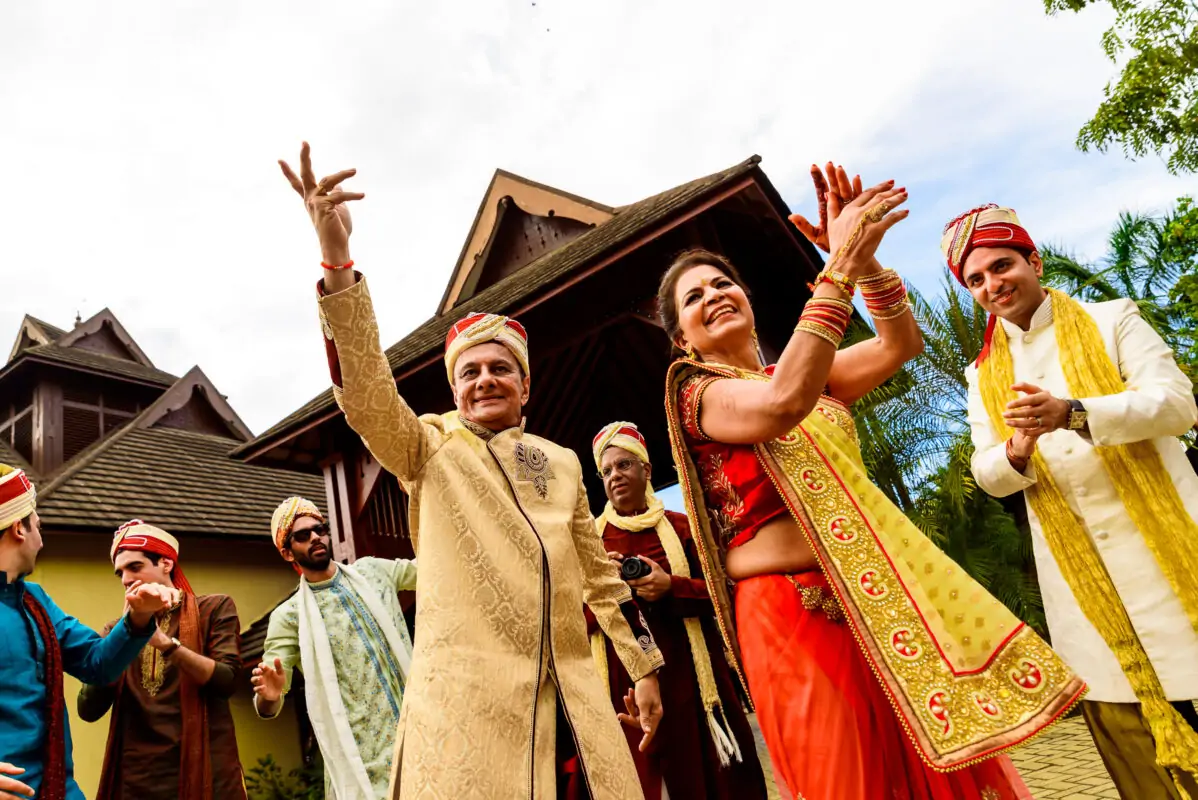 A group of indian people dancing in front of a house.