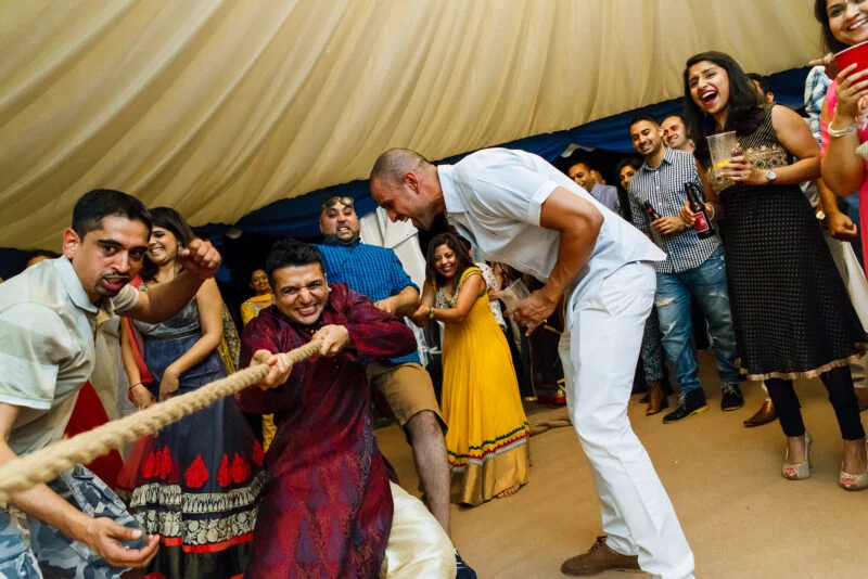 A group of people playing tug of war at an indian wedding.