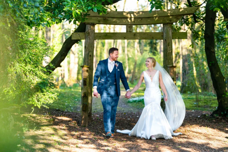 A bride and groom captured by the best wedding photographer in Bristol as they walk through a wooden gate in the woods.
