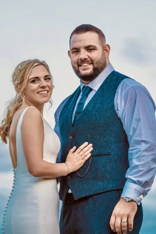 A bride and groom posing for a photo on the beach.