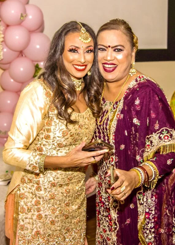 Two indian women posing for a photo at a party.