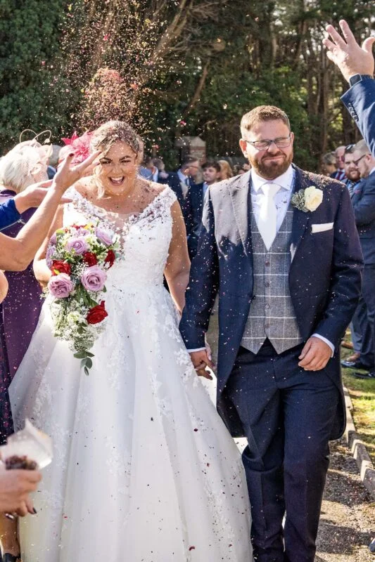 A bride and groom walking down the aisle with confetti thrown at them.