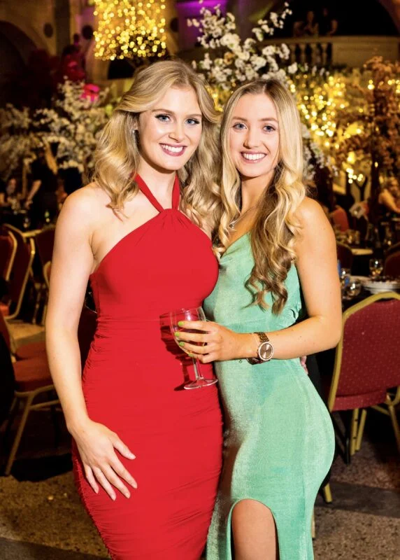 Two women posing for a photo in a fancy dress.