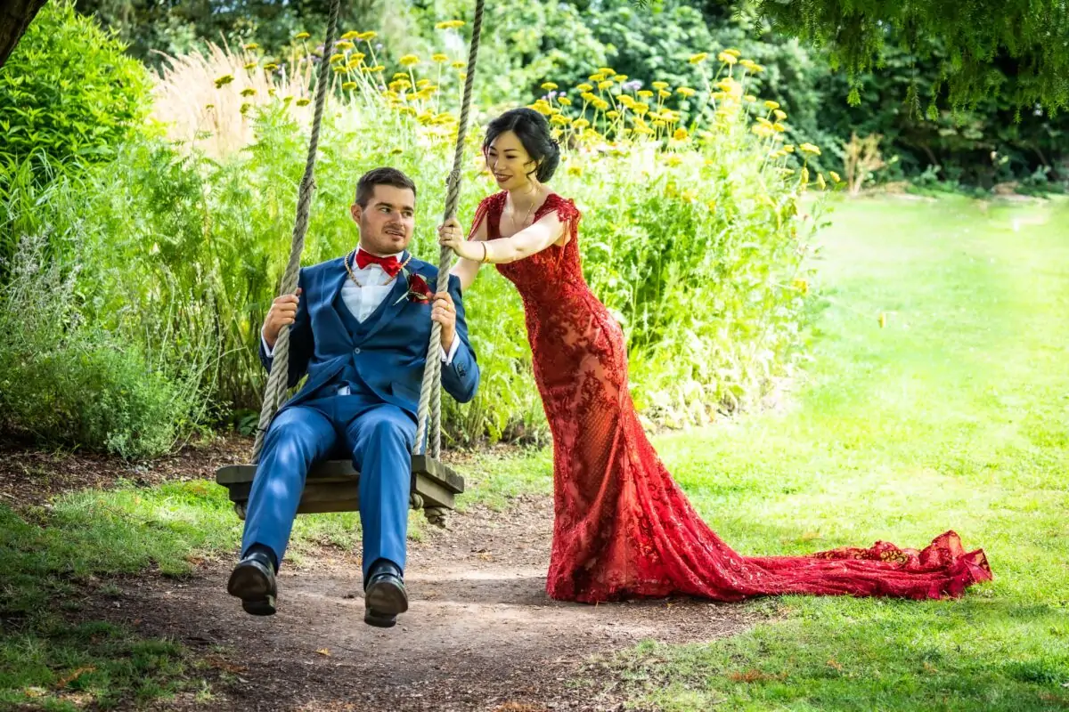A bride and groom on a swing in a garden.