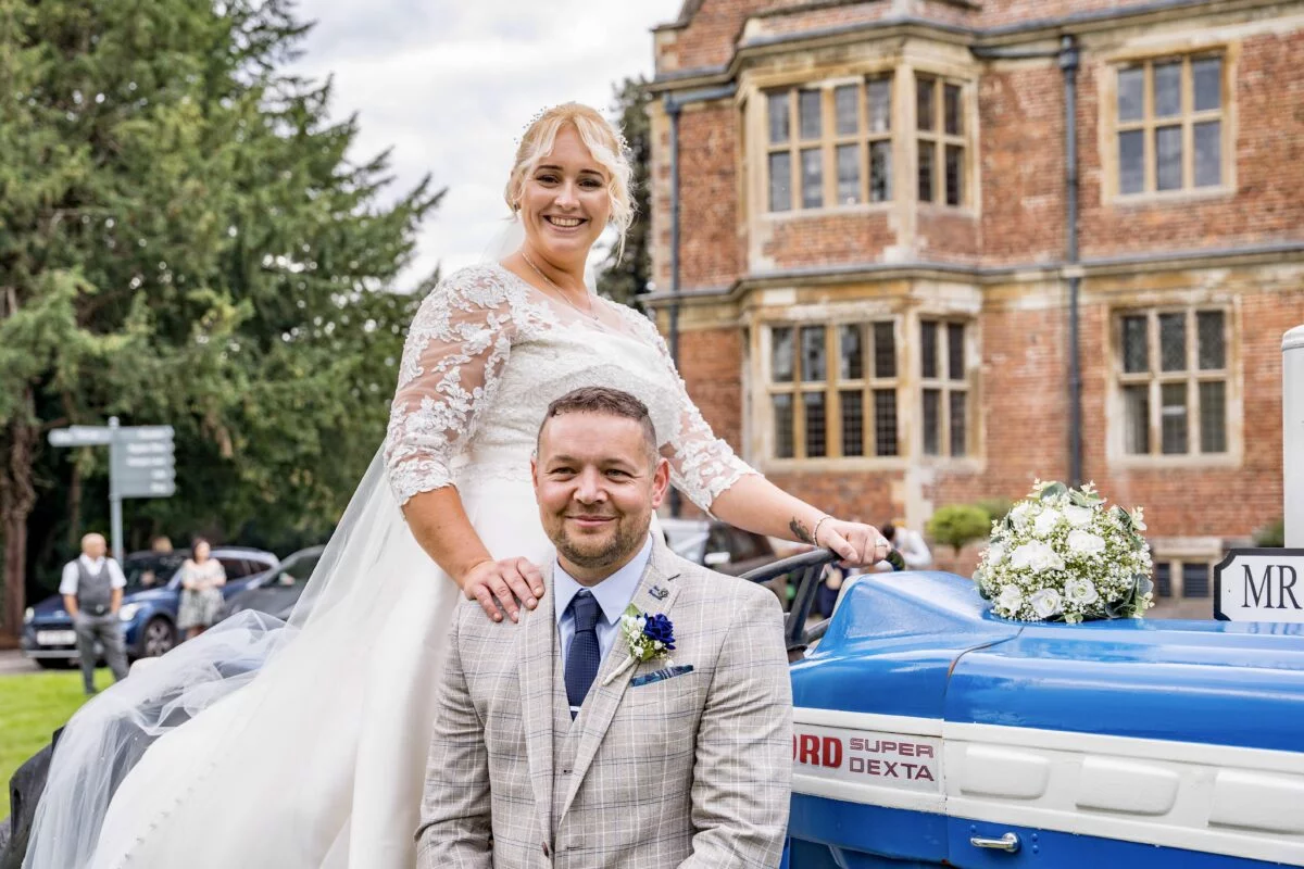A bride and groom posing next to a blue vintage car.