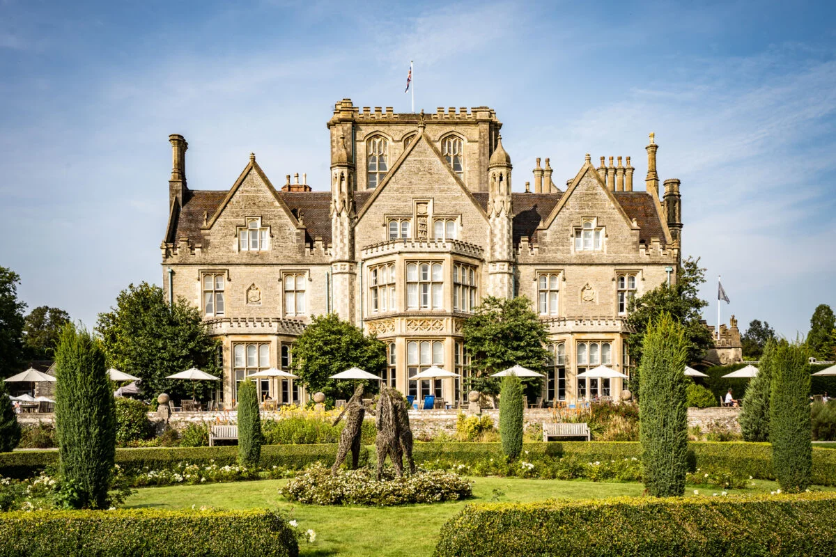 A large manor house with a garden in front of it.