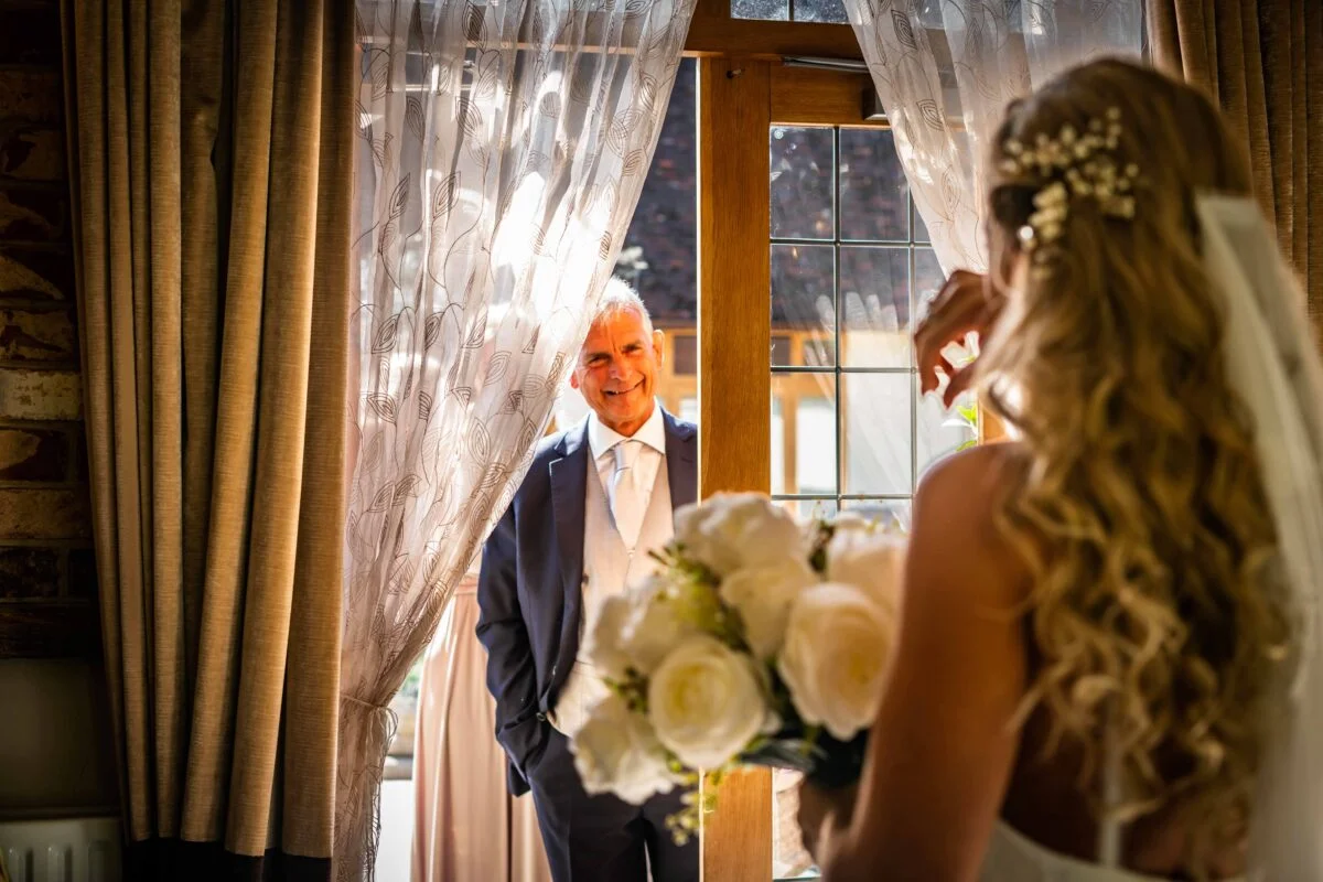 A bride and groom looking at each other through a window.