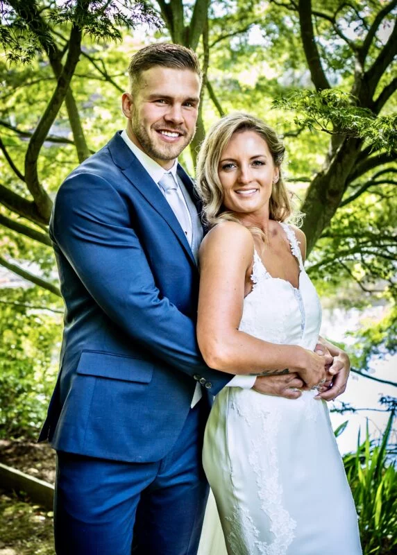 A bride and groom posing in front of a tree.
