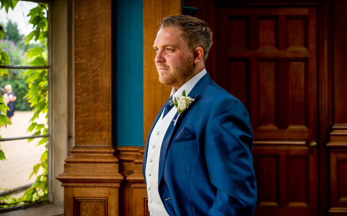 A man in a blue suit standing in front of a window.