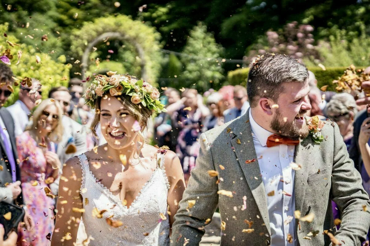 A bride and groom walk down the aisle with confetti thrown at them.