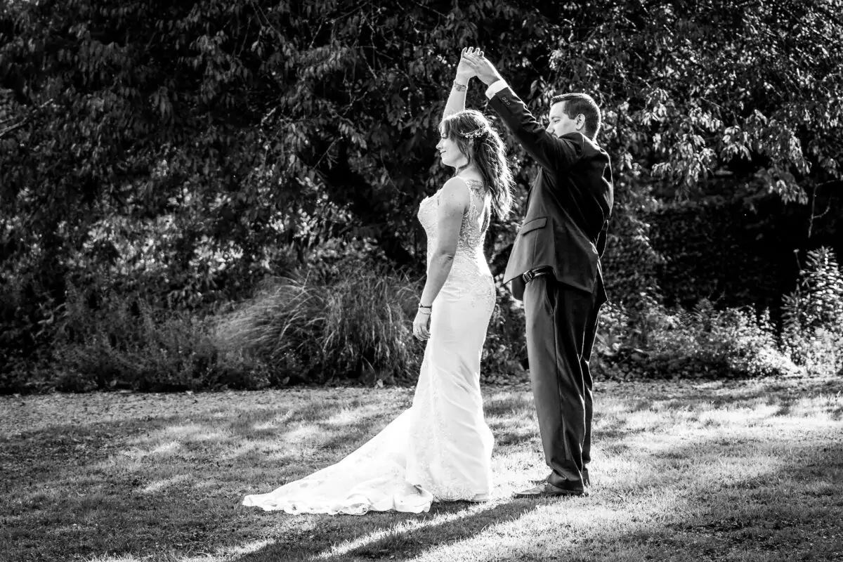 Black and white photo of a bride and groom dancing in the grass.