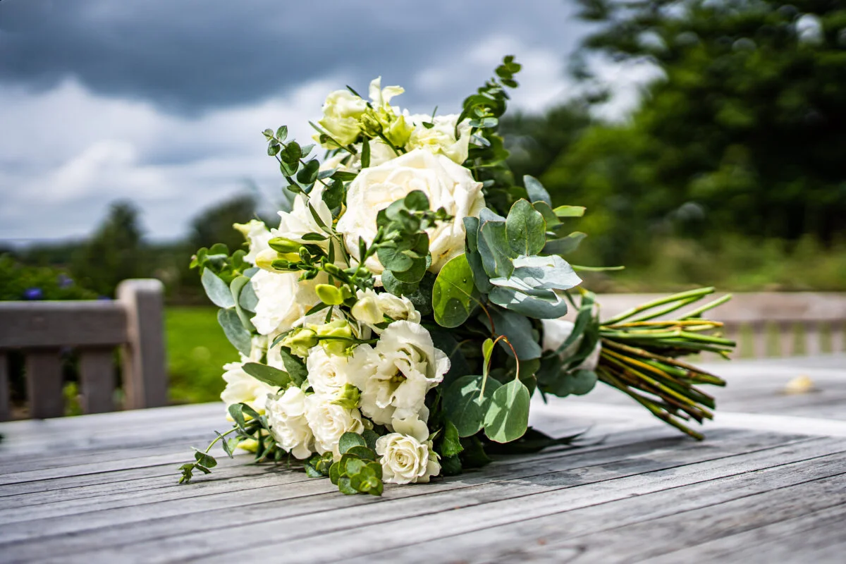 A white bouquet sits on a wooden table.