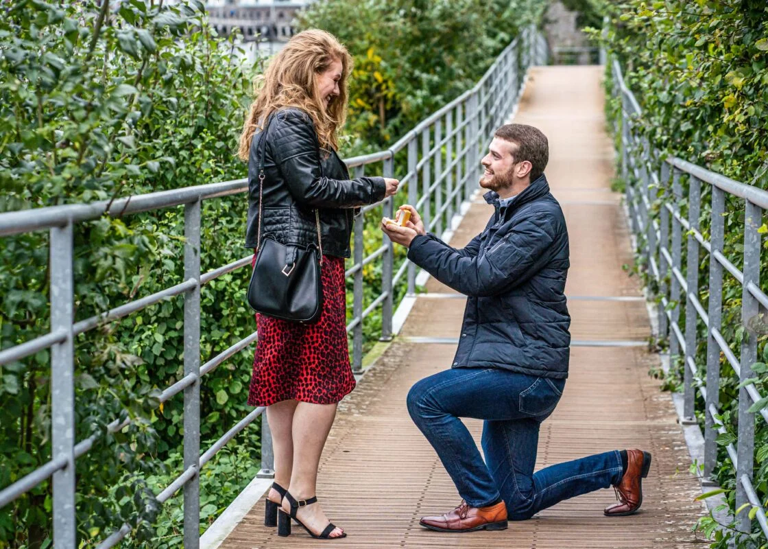 A man proposes to a woman on a bridge.