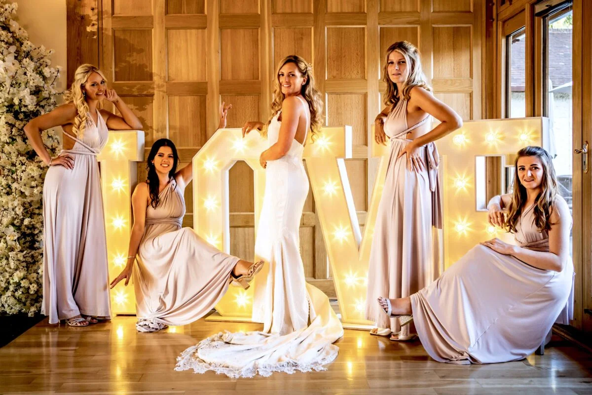 Bridesmaids posing in front of the word love.