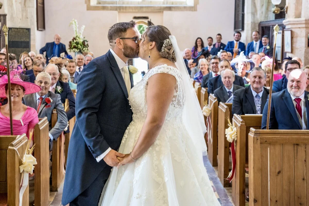A bride and groom kissing in a church.